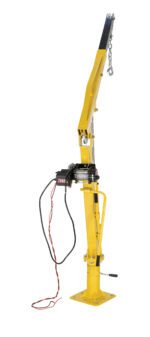 The Vestil Winch Operated Truck Jib Crane - DC boasts a yellow hydraulic design with a steel arm and electric winch. A chain graces the arms end, accompanied by red and black cables, all mounted on a stable rectangular platform.