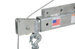 A close-up of a silver bracket with a hook and cable displays a Made in U.S.A. sticker and American flag. Its crafted for the Vestil Dc Power Jib Crane 1.5K 66 In Boom Galv, featuring a durable galvanized finish on its 66-inch boom.