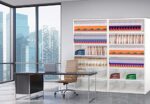 The modern office showcases a sleek desk and leather chair, highlighted by the Aurora Quik-Lok Shelving Add-On Unit with six adjustable openings for organization. Large windows frame city views, while a white bookshelf stores multicolored folders in a bright, organized setting.