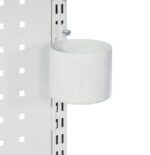 A metal cup holder is attached to a perforated white panel. The holder is cylindrical, and secured with a screw to the panel. The panel has a grid of square holes, and the cup holder is positioned near the edge.