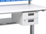 A white workbench with two metal drawers beneath the tabletop embraces a laboratory design. The recessed drawer handles and sturdy, industrial build offer functionality. A portion of a blue storage bin is visible on top, adding a splash of color to the scene.