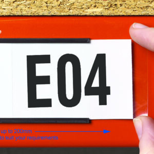 A hand inserts a label with E04 printed on it into a black holder. The holder is attached to a red surface. Blue text indicates the features: available in 10 different heights, and pre-cut lengths up to 200mm or custom lengths.