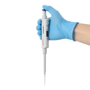 A gloved hand holds a laboratory pipette with a digital display. The pipette is white with blue accents and features measurement markings. The background is plain white.