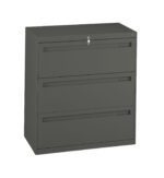 A gray, three-drawer filing cabinet with a lock at the top. The cabinet is square-shaped and appears to be made of metal. Each drawer has a handle for opening.