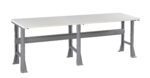 A long, rectangular workbench with a white tabletop and sturdy grey metal legs. The bench has a solid frame with horizontal support beams, suitable for industrial or workshop use. The design is minimalist and functional.