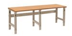 A long, sturdy workbench with a wooden top and beige metal frame, featuring adjustable legs for height variation, set against a plain white background.