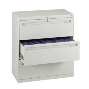 A white metal filing cabinet with two drawers. The top drawer is closed and locked, while the bottom drawer is partially open, revealing organized files. The cabinet is set against a white background.