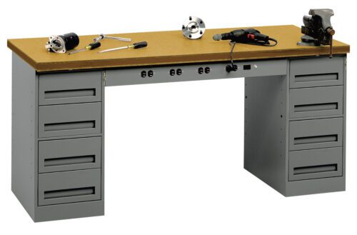 A sturdy workbench with a wooden top and two sets of metal drawers on each side. Tools are scattered on the surface, including a drill, a clamp, and wrenches. The drawers have handles for easy access.