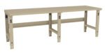 A long, beige workbench with adjustable legs and a flat surface. The design is simple and industrial, with visible holes in the legs for customization of height. Suitable for a workshop or garage setting.