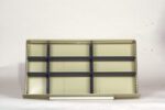 An empty beige shelf with multiple compartments and black horizontal dividers against a light background.