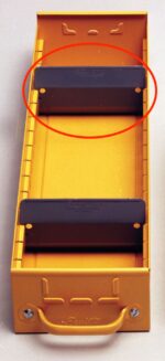 A yellow metal box with a handle at the bottom and two black bars mounted inside. One of the black bars is circled in red. The box has a rectangular shape and includes grooves along the sides.