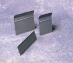 Three gray plastic rectangles with beveled edges and slight ridges are standing upright on a textured gray surface. Two are vertical, while one leans slightly.