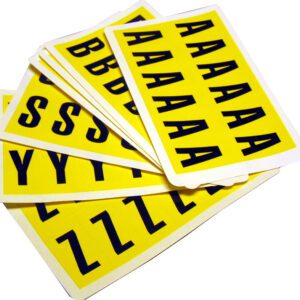 A stack of MH-USA Complete Packs of Self-Adhesive Letters - H.0.83 in. x W.1.5 in. - features black uppercase letters on yellow sheets like A, B, S, Y, and Z, arranged in an overlapping fan-like style to add creativity to any project.