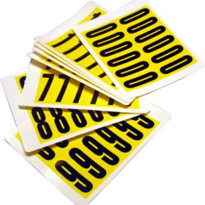 A stack of MH-USA Complete Packs of Self-Adhesive Numbers in yellow, featuring bold black digits like 0s, 1s, 8s, and 9s on each card. Measuring H.0.83 in. x W.2.2 in., these numbers ensure clear visibility.