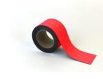 A roll of MH-USA Magnetic Easy-Wipe Strip in red with a black interior partially unrolls on a white surface, showcasing its smooth, glossy finish with an upwardly curved loose end.