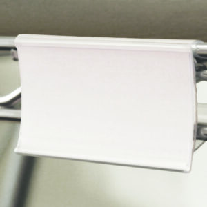 A blank white paper is attached to a metal hanger using an MH-USA Wire Shelving Clip Holder - Pack of 12 - H.1.69 in. x W.2.95 in., set against a neutral backdrop.