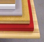 A stack of different materials is arranged on a table. From top to bottom: white rectangular block, gray foam pad, cork board, wooden board, and red fabric. The background is a gray floor.