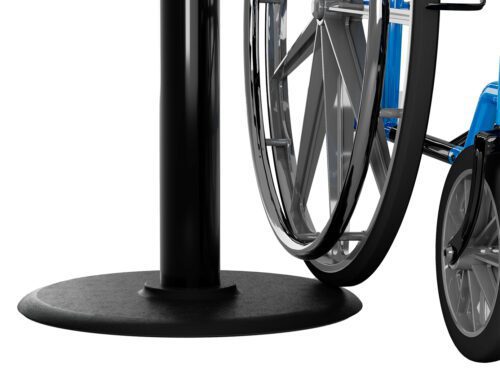 A shiny silver wheelchair wheel is positioned next to a Visiontron Value Series Black Steel Retractable Belt Stanchion with a 7.5 belt, set against a white background to highlight their contrasting elements.