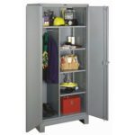 A gray metal storage cabinet with an open door, revealing five shelves. Items include a yellow hard hat, black flashlight, green safety vest, red toolbox, boots, and various cans and tools. A dark jacket hangs on the left side.