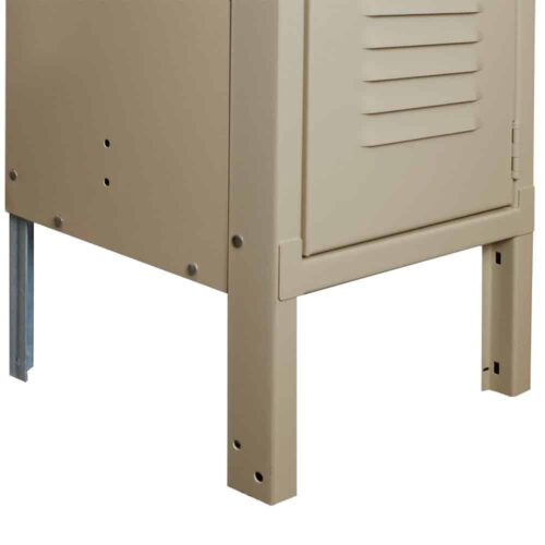 Close-up view of the lower section of a beige metal cabinet with vented doors. The cabinet stands on four legs, two of which are metal, and features visible screws on its side and corner.