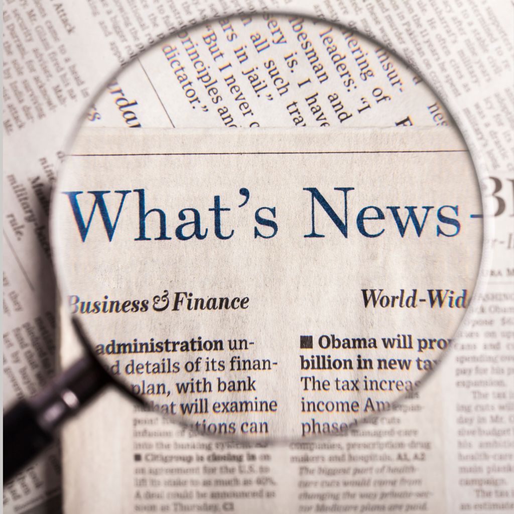 A newspaper page with a magnifying glass highlighting the headline Whats News, featuring sections like Business & Finance and World-Wide. Among the stories is a piece on the PUMP Act, discussing new lactation pods in airports. The text is printed in black on slightly yellowed paper.