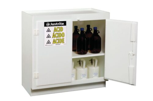 The Justrite Cabinet Acd, Poly Standing, Wh is opened, showcasing shelves with brown bottles and white containers. A label on the door reads Justrite Acid Ácido Acide with warning symbols for safe hazardous material storage.