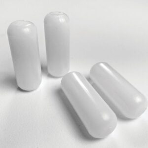 Four white plastic caps, resembling the minimal design of Justrite Poly Shelf/Pegs 24010 & 24015, sit on a white surface. Two stand upright while two lie sideways, highlighting their cylindrical shape with rounded tops and flat bases.