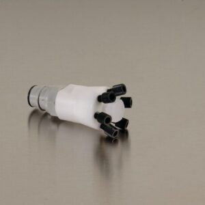 Close-up of a mechanical device with five black, flexible extensions on a cylindrical white base, resembling robotic fingers or a gripper on a reflective surface, showcasing innovative elements akin to the Justrite Manifold, Poly W/Poly Qd for superior functionality.