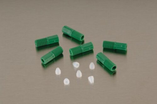 Seven green, ribbed cylindrical Justrite Fitting F/Hrd Wall Tube 1/8Od with threaded ends and white, translucent cone-shaped pieces are scattered on a beige surface.