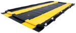 A Washdown 12X26X4 Justrite Berm in black and yellow lies flat on the ground, featuring strong side walls for leak or spill containment. The contrasting colors boost visibility and safety.