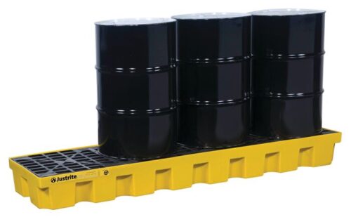 Three black industrial barrels are securely placed on a grated surface of the Justrite Pallet, 4 Drum Inline, Eco Yel, expertly designed to hold them safely in place.