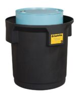 A blue drum rests inside a black spill containment basin with a yellow Justrite Collection Ctr Sgl Drm, Eco Bk label. The basin has robust vertical ridges for secure and eco-friendly containment.