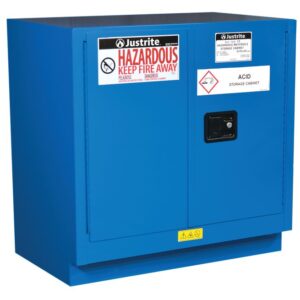 The blue Justrite Cabinet, Haz M U/C Chmc 22G Sc, is labeled Hazardous Keep Fire Away and Acid Storage Cabinet, features two doors and a black handle on the right door, and is designed for safety on flat surfaces.