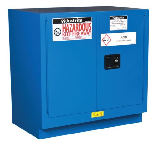 The blue Justrite Cabinet, Haz M U/C Chmc 22G Sc, is labeled Hazardous Keep Fire Away and Acid Storage Cabinet, features two doors and a black handle on the right door, and is designed for safety on flat surfaces.