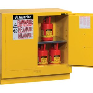 A yellow Justrite Cabinet, model Flam U/C 22G Sc Yel, stands open, revealing three red safety cans on two shelves with a flammable hazard warning label and prominently displaying the manufacturers name.