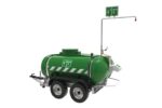 The Justrite H,Showr/Efwsh,Mobile,528G,120V emergency portable shower unit is green and features safety signage. It is mounted on a wheeled trailer with two axles and four wheels and includes a 120V system with a shower head plus various controls and gauges for optimal use.