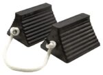 A pair of black, ribbed Justrite 10 pyramid chocks with a white rope handle prevents vehicles from moving.