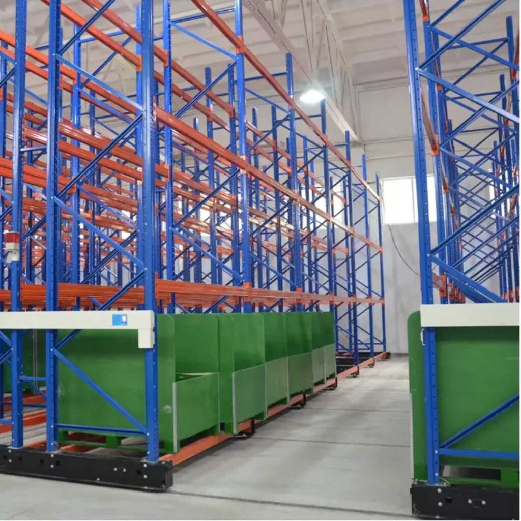 The warehouse interior is equipped with tall, blue and orange heavy-duty racks, featuring green partitions at the base. Its high ceiling and strategically placed light source ensure even illumination throughout the space.