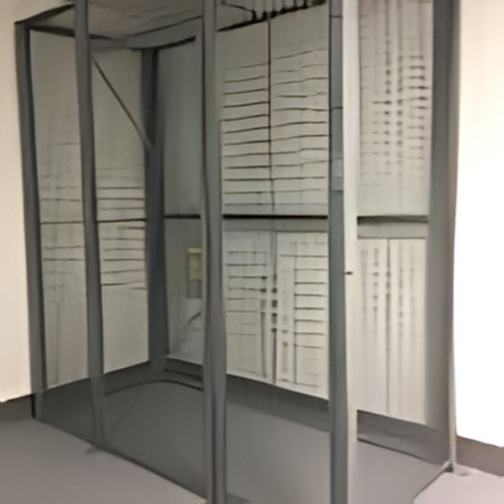 A minimalist indoor structure with translucent, vertical panels forming three sides, reminiscent of lockers. The panels are divided into rectangular sections like large window panes. The interior remains bare, creating a sense of openness and simplicity.