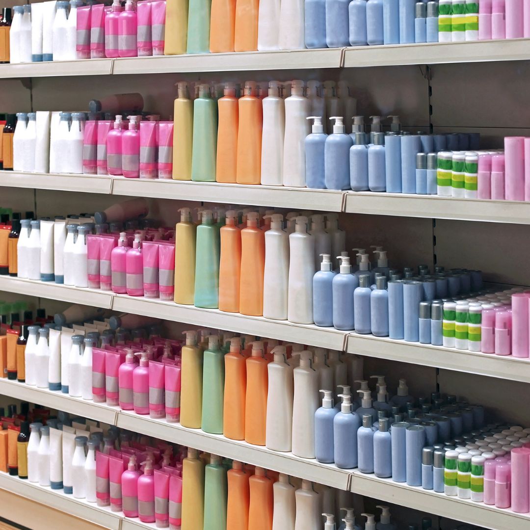 Shelves filled with variously colored bottles of personal care products are neatly arranged on durable organizational shelves. The bottles, in shades of pink, orange, blue, green, and white, sit perfectly aligned. The aisles appear well-organized and fully stocked.