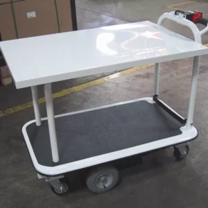 A white Electro Kinetic Technologies Pony Express Motorized Platform Truck, boasting a 1500 lb. capacity and (2) shelving units of 26 wide x 40 long, is parked in an industrial setting with marked yellow guidelines on the concrete floor. It features a handlebar and four wheels.