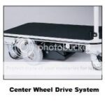 The Pony Express Motorized Platform Truck by Electro Kinetic Technologies, with a 1500 lb. capacity, showcases a center wheel drive system on its sleek design, featuring a black surface and white frame measuring 49 L x 25 1/2 W usable deck. Center Wheel Drive System text is displayed at the bottom.