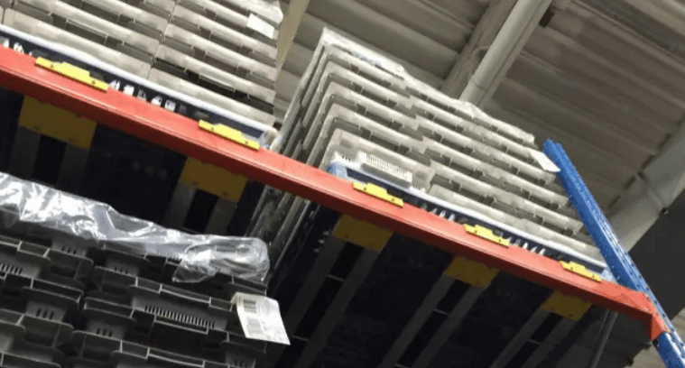 Stacked pallets rest securely on a high industrial shelf, utilizing a Pitch-Rail Pushback Pallet Rack system for efficient storage and easy access.