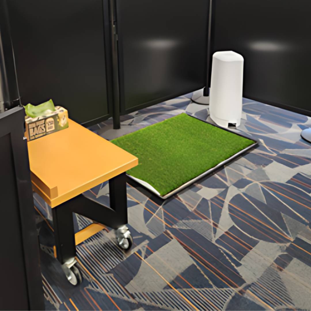 This well-organized office space features black partition walls, a movable yellow table, and a large green mat complementing the decor. A white cylindrical object rests on the patterned carpet, while the tissue box on the table suggests readiness for any task—even traveling with our pets in mind.