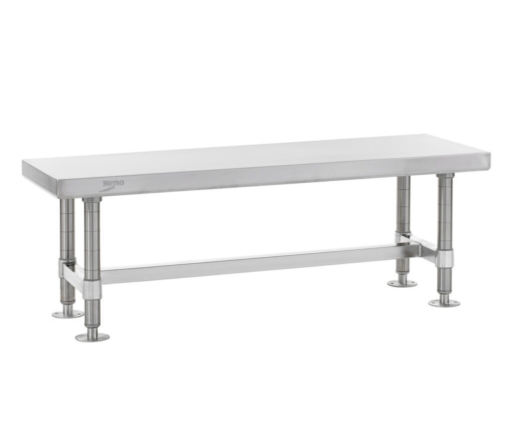 A sleek, rectangular stainless steel bench with four round legs connected by horizontal supports. The smooth, reflective surface is an ideal choice for gowning room essentials in industrial or commercial settings.