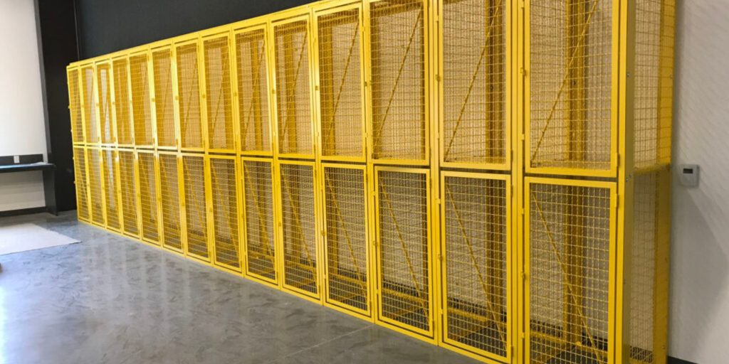 A row of yellow wire tenant lockers lines the wall, their tall and narrow metal mesh panels perfectly complementing the polished concrete flooring. These industrial storage solutions are your ultimate source for tenant lockers.