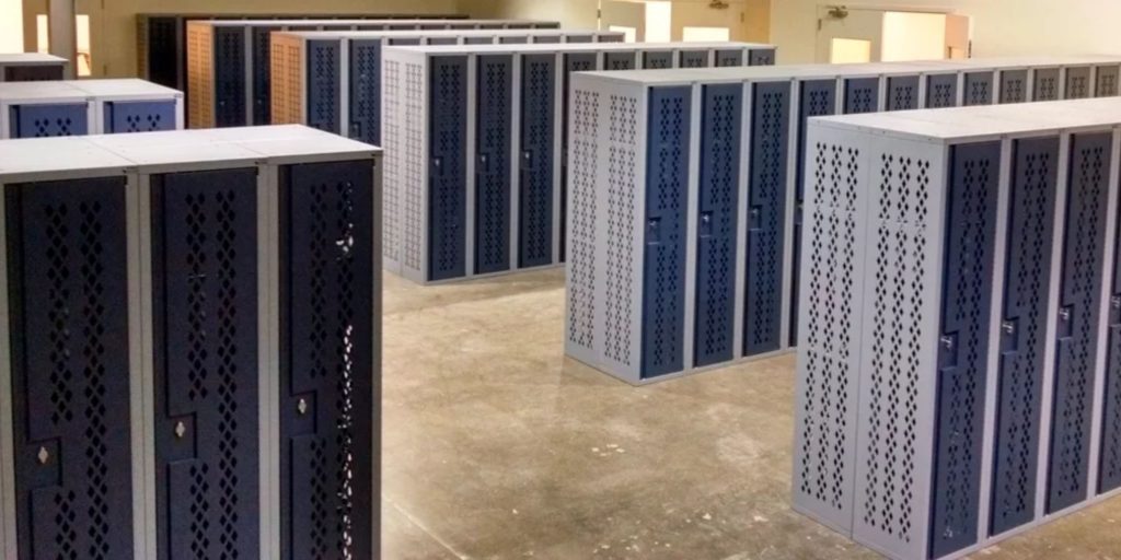 A room filled with rows of blue metal lockers, reminiscent of datum storage units, is arranged on a polished concrete floor. The lockers are neatly aligned, with natural light streaming through partially visible windows in the background.