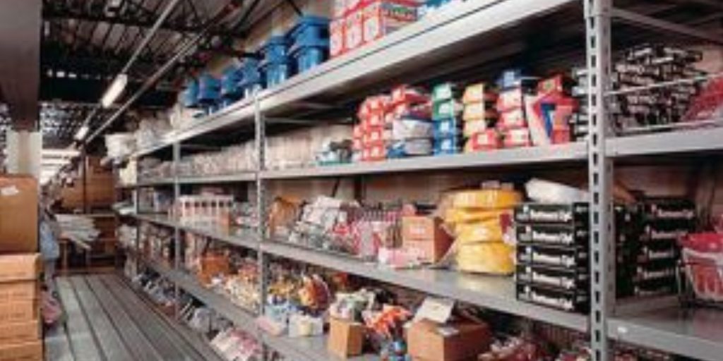 Shelves brimming with tools and hardware, featuring boxes, plastic containers, and packaged goods, are neatly organized in a warehouse aisle. Discover efficient organization with Penco Products material handling solutions to streamline your storage needs.