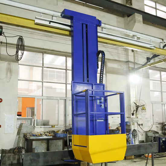 A blue and yellow industrial lifting platform with a safety cage is attached to a vertical rail inside a factory with large windows and various equipment in the background.
